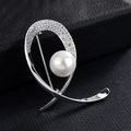 Vue macro d'une broche argentée élégante avec perle blanche et strass sur cuir noir - Poisson Géométrique