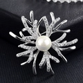 Détail macro d'une broche corail argentée avec zircons brillants et une grande perle blanche - Flocon de Neige Bois