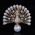 Detailed close-up of a gold peacock brooch with white zircons and a large pearl drop - Gold White Zirconia