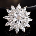 Elegante broche de flor dorada con pétalos de circón en superficie negra reflectante - Dorado
