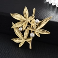 Elegante spilla a foglia di bambù in oro opaco con tre perle bianche su sfondo nero - Oro