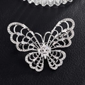 Détail macro de broche papillon argentée avec zircons sur cuir noir texturé - Papillon Argent