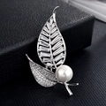 Détail macro d'une broche feuille argentée avec zircons rectangulaires et une perle blanche - Perle à Deux Feuilles