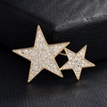 Détail d'une broche à double étoile dorée avec zircons blancs sur cuir noir foncé - Étoiles Jumelles