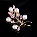 Élégante broche feuille dorée avec perles blanches et cristaux roses sur fond noir poli - Or