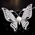 Macro shot of silver butterfly brooch featuring cubic zirconia and central pearl detail - Butterfly