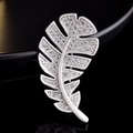 Elegant silver feather brooch with sparkling crystals on a sleek black background - Feather