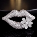 Detailed close-up of a silver lip-shaped brooch with clear zircons on black mirror surface - Lips