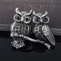 Vintage owl brooches with grey rhinestones on a tree branch with reflective surface - Double Owl Style / Antique Silver
