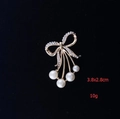 Detail view of gold bow brooch with sparkling rhinestones and elegant white pearls - Bowknot Grape