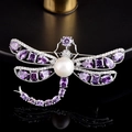 Détails de broche libellule avec gemmes violettes et perle blanche sur un support sombre - Libellule En Zircon Violet