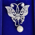 Elegante spilla a farfalla con zirconi e perla bianca pendente su velluto blu - Argento