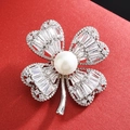 Elegante spilla a quadrifoglio in argento con zirconi e perla centrale su fondo rosso - Stile Perla