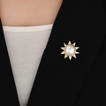 Detailansicht der Sonnenblumen-Magnetbrosche mit Perle und Kristallen auf schwarzem Blazer - Gold