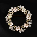 Eleganter runder Blumen-Anstecker mit Zirkonia und Opal-Effekt auf schwarzem Hintergrund - Gold