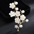 Elegante spilla a forma di fiore dorato con perle bianche e zirconi su sfondo nero - Oro