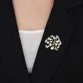 Dettaglio spilla albero della fortuna dorata con perle e zirconi su un blazer - Oro