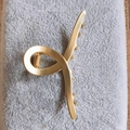 Detail of a matte golden cross metal hair claw clip with strong spring mechanism - Small Clip