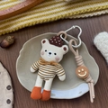 Detail of a handmade knitted beige bear pendant with heart clasp and wooden smile bead - Brown Striped Bear Style