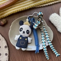 Detailed view of plush panda charm with crown, blue overalls, and woven blue tassel - Blue Overall Panda Style
