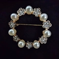 Elegant gold ring brooch with white pearls and sparkling crystal flowers on black background - Pearl Circle
