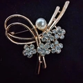 Elegant gold flower brooch with white pearl and sparkling rhinestones on black base - Spinning Pearl