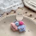 Nahaufnahme von Stern-Plüsch-Haargummis mit Gesichtern und Bommeln in Keramikschale - Pink und Blau Stern Haargummis