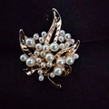 Golden maple leaf brooch pin with elegant white pearls on a dark velvet surface - Pearl Leaf