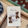 Dettaglio di due fermagli per capelli con fiocco marrone su carta e sfondo in tessuto rustico - Fermaglio a Fiocco Triangolare