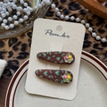 Vista detallada de dos horquillas con estampado de leopardo y pequeñas flores blancas - Estilo de Perla de Leopardo Café