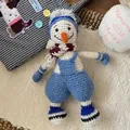 Detail of a handmade knitted snowman doll with blue hat, scarf, and cute denim overalls - Knitted Snowman Doll