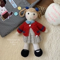 Detailed close-up of handmade knitted doll with brown braids and red cardigan sweater - Knitted Red Sweater Girl Doll