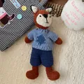 Detailed close-up of a handmade crochet fox doll wearing a blue knitted sweater on soft rug - Knitted Little Fox Doll