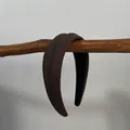Détail d'un serre-tête rembourré marron foncé avec texture côtelée sur une branche en bois - Serre-tête large rembourré café