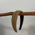 Détail d'un serre-tête en tissu texturé vert olive sur fond de branche rustique - Serre-tête large rembourré vert matcha