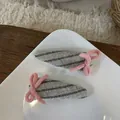 Detail von stoffbezogenen Haarklammern mit rosa Strickschleifen auf Keramikteller - Grau-Rosa Schleifen-Haarspange