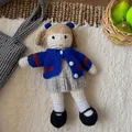 Detailed view of handmade wool felt girl doll with braids and a blue bow on textured background - Navy Blue Knitted Girl