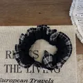 Detalle de coletero de cuadros con encaje y cuenta de resina en libro vintage - Cuadros Negro
