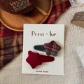 Detail of red and plaid star-shaped fabric hair clips on a white brand card display - Plaid Star Clip