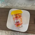 Close-up of assorted colorful kids hair ties in a transparent plastic jar with yellow lid - Yellow