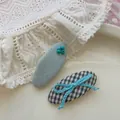 Détail de barrettes à carreaux bleus avec nœud et pinces brodées de perles sur un plateau - Nœud Perle Ovale Bleu