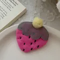 Détail macro d'une pince à cheveux fraise brodée rose sur une assiette blanche et dentelle - Forme de fraise / Pince à Fraise