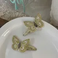 Dettaglio di fermagli per capelli a farfalla ricamati con paillettes dorate e tulle bianco - Clip Farfalla Giallo