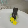 Détail d'élastiques à cheveux étoiles jaunes sur cordelette verte avec emballage de marque - Étoile Jaune
