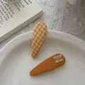 Détail de barrettes à carreaux jaunes et à froufrous orange sur une assiette blanche - Clip BB à Carreaux Orange