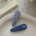 Détail de barrettes en tissu bleu à carreaux et à volants sur une assiette blanche - Clip BB à Carreaux Bleus