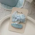 Dettaglio del fermaglio a fiocco blu e forcina in tweed su cartoncino espositivo - 亮片蝴蝶结+水滴发夹