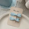 Détail des barrettes à nœud bleu avec bords brodés présentées sur une carte de support - Pince À Cheveux Nœud Imprimé