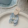 Vue détaillée du nœud papillon en tulle bleu clair avec perle sur une assiette blanche - 纱质蝴蝶结发圈