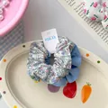 Close-up of floral fabric hair scrunchie with blue stitching on a decorative plate - Blue Floral Small Scrunchie